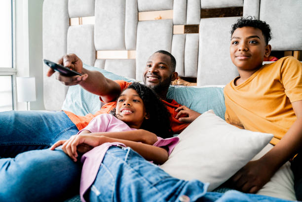 Family watching tv on bedroom at home